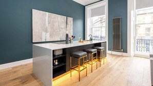 A modern kitchen with a bar area, a large window, and a radiator.
