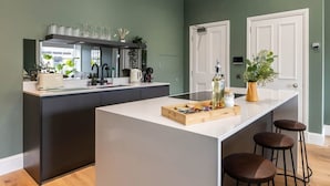 A modern kitchen with a central island, bar stools, and a view of the outdoors. - Jade Suite - City Centre 2 Bed Luxury Apartment (Edinburgh)