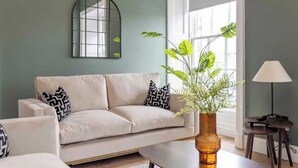 A living room with a sofa, a coffee table, a lamp, a mirror, and a plant. - Jade Suite - City Centre 2 Bed Luxury Apartment (Edinburgh)