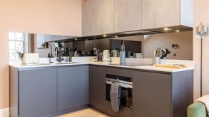 Et moderne køkken med en stor køkkenø, indbyggede hårde hvidevarer og et stort vindue.