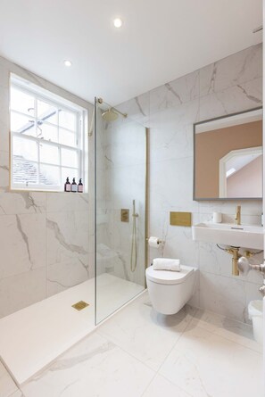 Enjoy a refreshing shower in the bathroom, featuring a glass-enclosed shower, white toilet, and sink with a gold faucet.