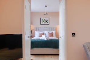 Restful retreat with a neatly made bed, framed artwork, and a single pendant light.