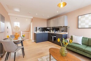 Enjoy breakfast at the dining table, surrounded by a vase of sunflowers and a comfortable sofa.