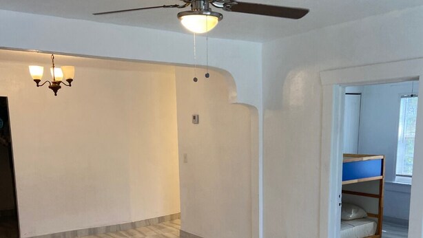 Ein geräumiges Zimmer mit Deckenventilator, einer Kristallleuchtre und einem Stockbett in der Ecke.