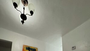 Ein Essbereich mit Tisch und Stühlen, einer Deckenleuchte und einem Wandbild.