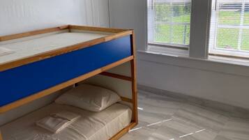Cozy room with a bunk bed featuring a top and bottom mattress, large window, and light-colored tiles.