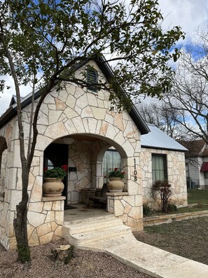 Une maison en pierre avec une entrée en arc de cercle, un petit porche et le numéro « 108 » peint sur le mur.
