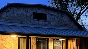 A stone building with a covered porch, a bench, and a table. - Centrally located Turn of the Century Beauty! (Kerrville)