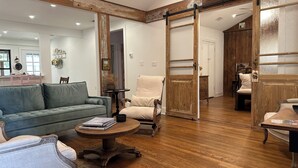 A spacious living room with a wooden floor, a sofa, a chair, and a table. - Centrally located Turn of the Century Beauty! (Kerrville)