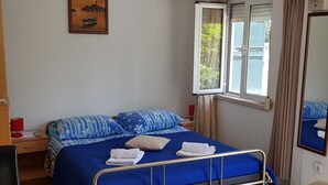 Un dormitorio con cama, mesita de noche, ventana y espejo.