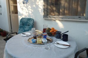A round table with a white tablecloth, a metal tray with food items, a glass pitcher, and a blue mug. - Apartment Mateo Lapad - Studio Apartment With Terrace and Garden View (Dubrovnik)