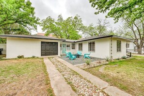 Ein eingeschossiges Haus mit Garage, einer Veranda mit Sitzgelegenheiten und einer kleinen Terrasse.
