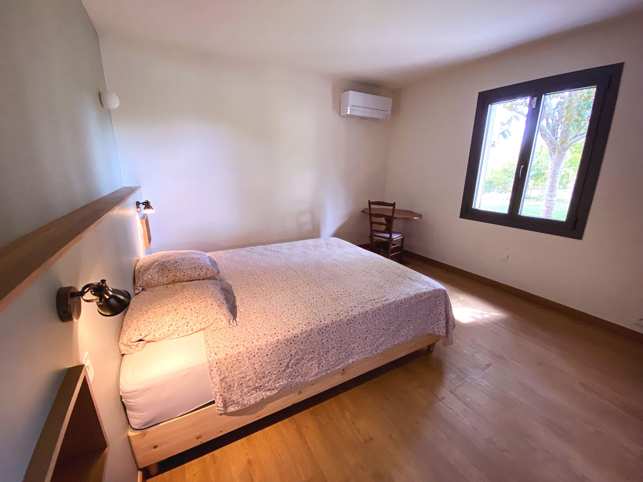 Une chambre à coucher avec un lit, une chaise, une table et une fenêtre.