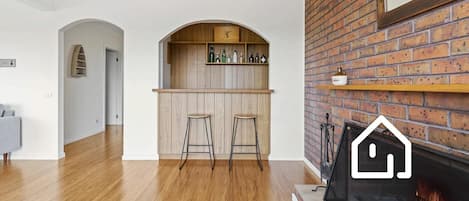 Une cuisine moderne avec un bar en bois, deux tabourets et une cheminée en briques.