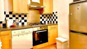 A kitchen with wooden cabinets, a gas stove, a built-in oven, and a stainless steel refrigerator. - Attractive Tower Bridge Apartment! 2 mins from the river side! (LONDON)