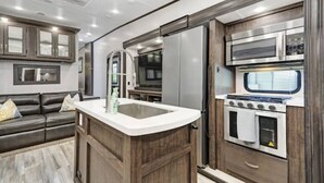 Una cucina moderna con isola centrale, elettrodomestici in acciaio inossidabile e mobili in legno scuro.