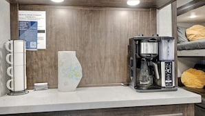 Un angolo cottura con una macchina del caffè, un portabicchieri e un vaso decorativo.