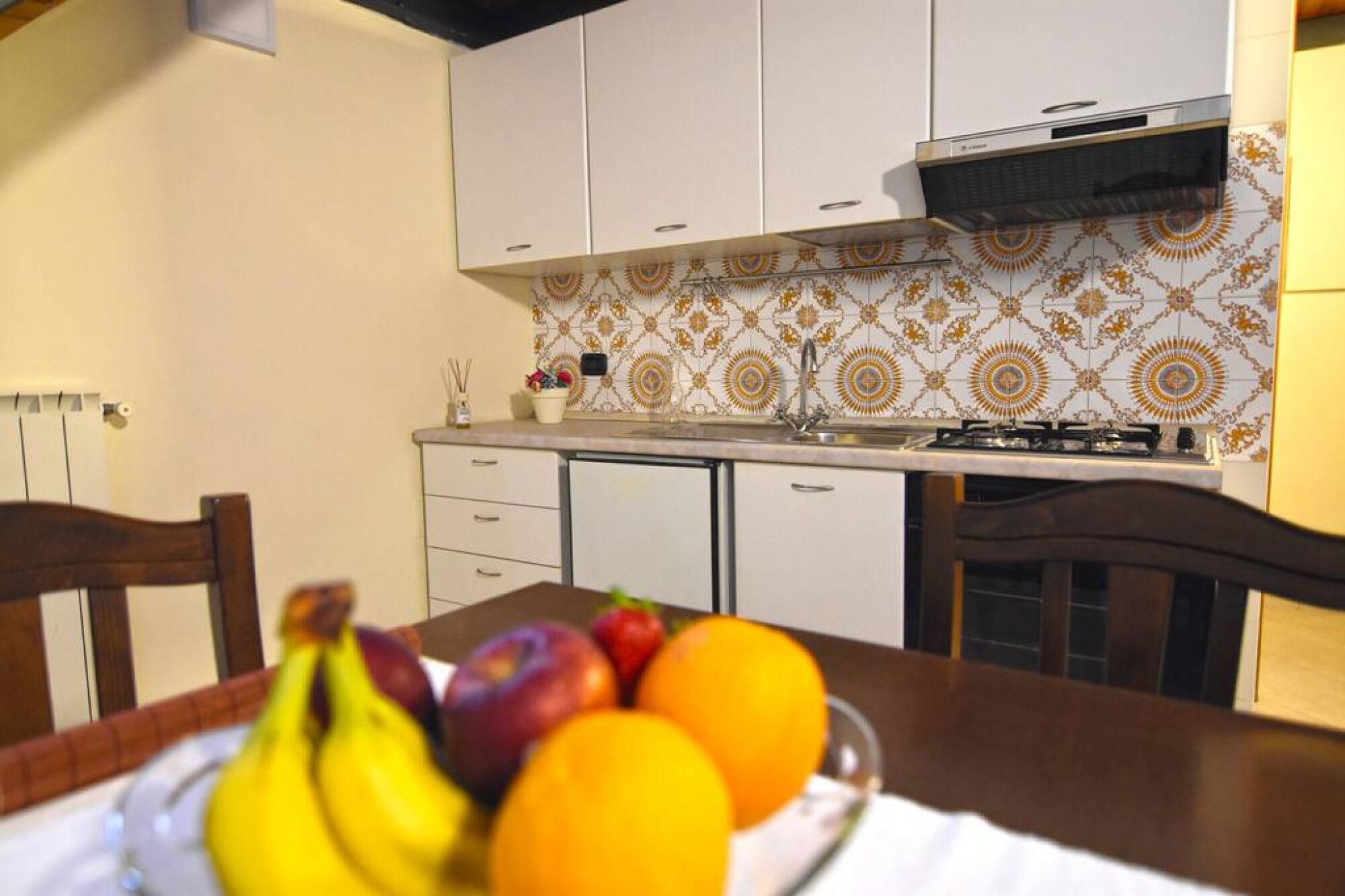 A kitchen with white cabinets, a stove, and a patterned backsplash.