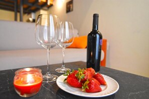 A table with a candle, two wine glasses, a bottle of wine, and a plate of strawberries.