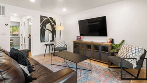 Un salon moderne avec un canapé en cuir, une table basse, un téléviseur et un meuble.