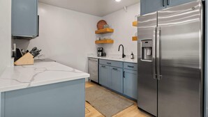 A modern kitchen with a stainless steel refrigerator, blue cabinets, and a marble countertop. - Walk to Downtown • Private Patio • Hot Tub + BBQ (Moab)