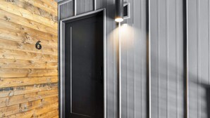 A modern elevator with a black door and a light fixture above it. - Walk to Downtown • Private Patio • Hot Tub + BBQ (Moab)