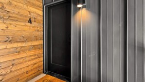 Um interior moderno com parede de madeira, porta preta e luminária vertical.
