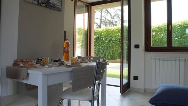 Un coin repas avec une table mise pour le petit-déjeuner, une bouteille de jus d’orange et un tableau accroché au mur.