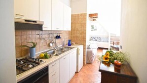 A compact kitchen with white cabinets, a gas stove, and a sink. - Case Cosi Napoli - APP 17 (Naples)