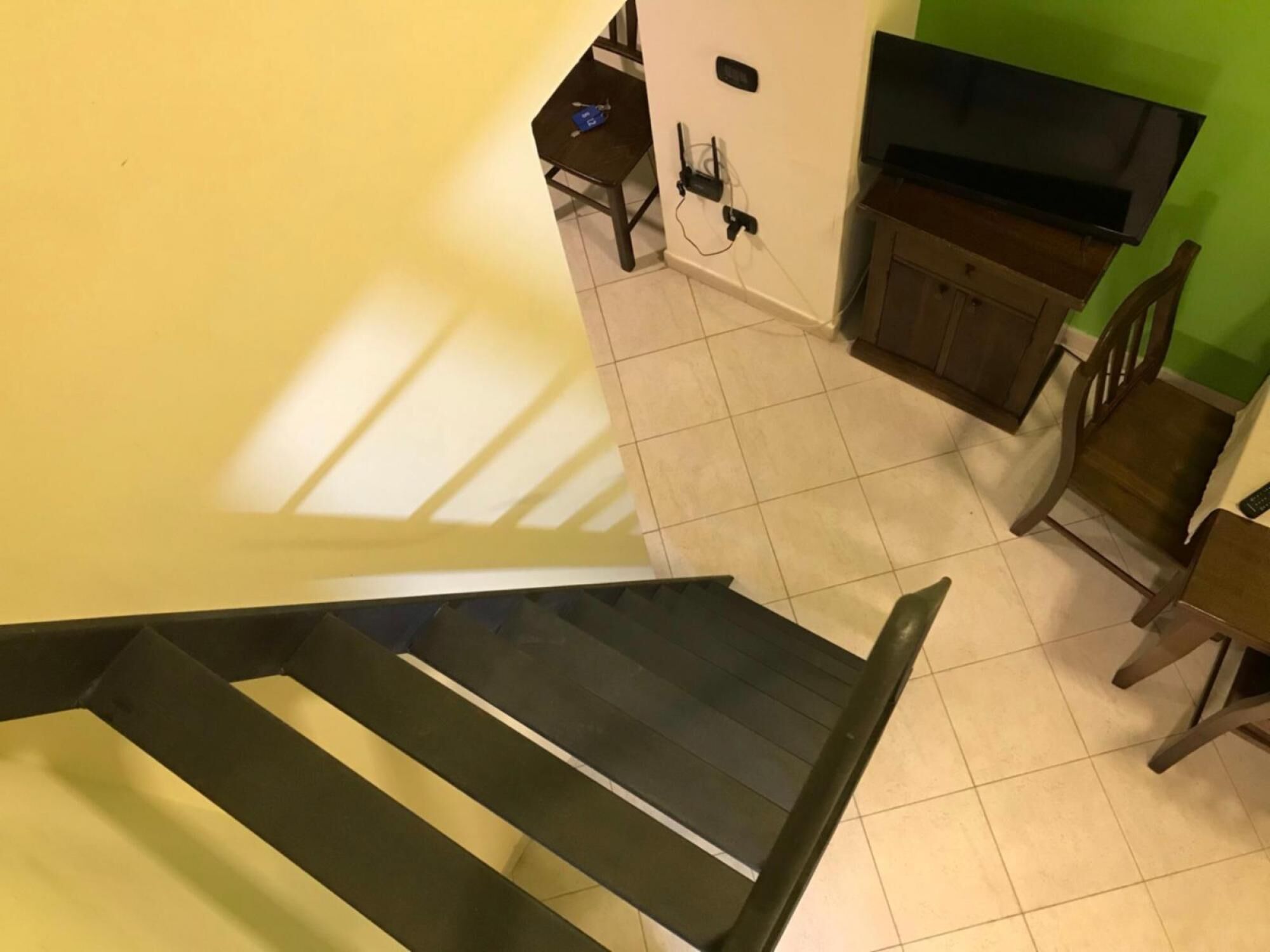 A staircase leading to a room with a green wall and a TV.