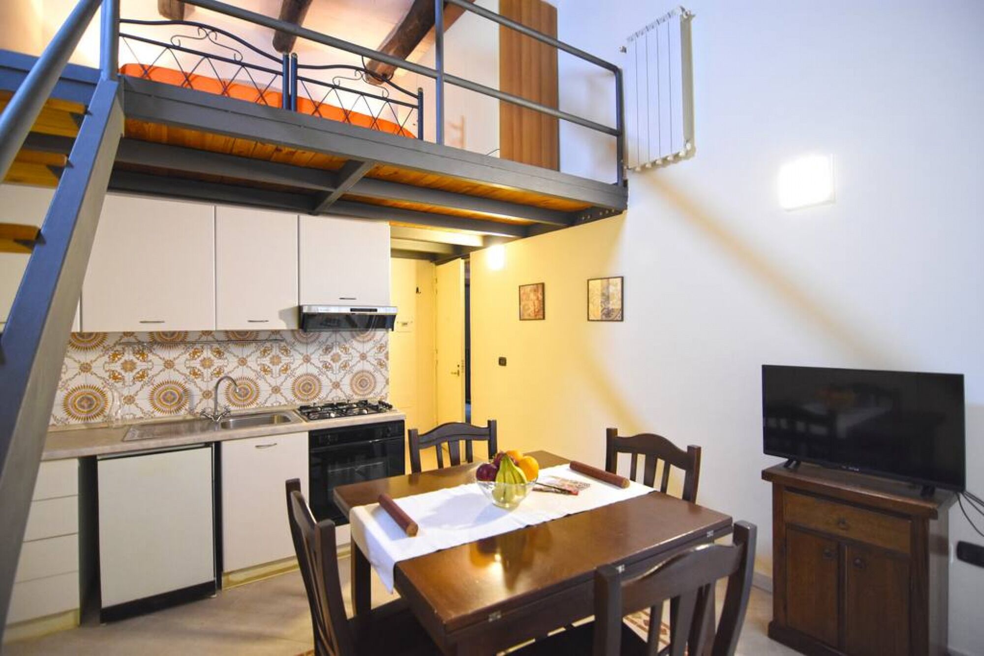 A compact kitchen with a gas stove, white cabinets, and a dining area with a table set for two.