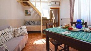 Een gezellige kamer met een bed, een eettafel gedekt met eten, een trap en een airconditioning.