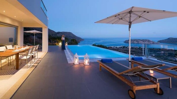 Une terrasse extérieure moderne avec une piscine, des chaises longues et une vue sur la mer.