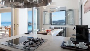 Une cuisine moderne équipée d’une cuisinière à gaz, d’une machine à café et d’un coin repas offrant une vue sur la mer.
