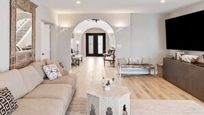 Una sala de estar moderna con un sofá, una mesa de centro y un televisor sobre un mueble.
