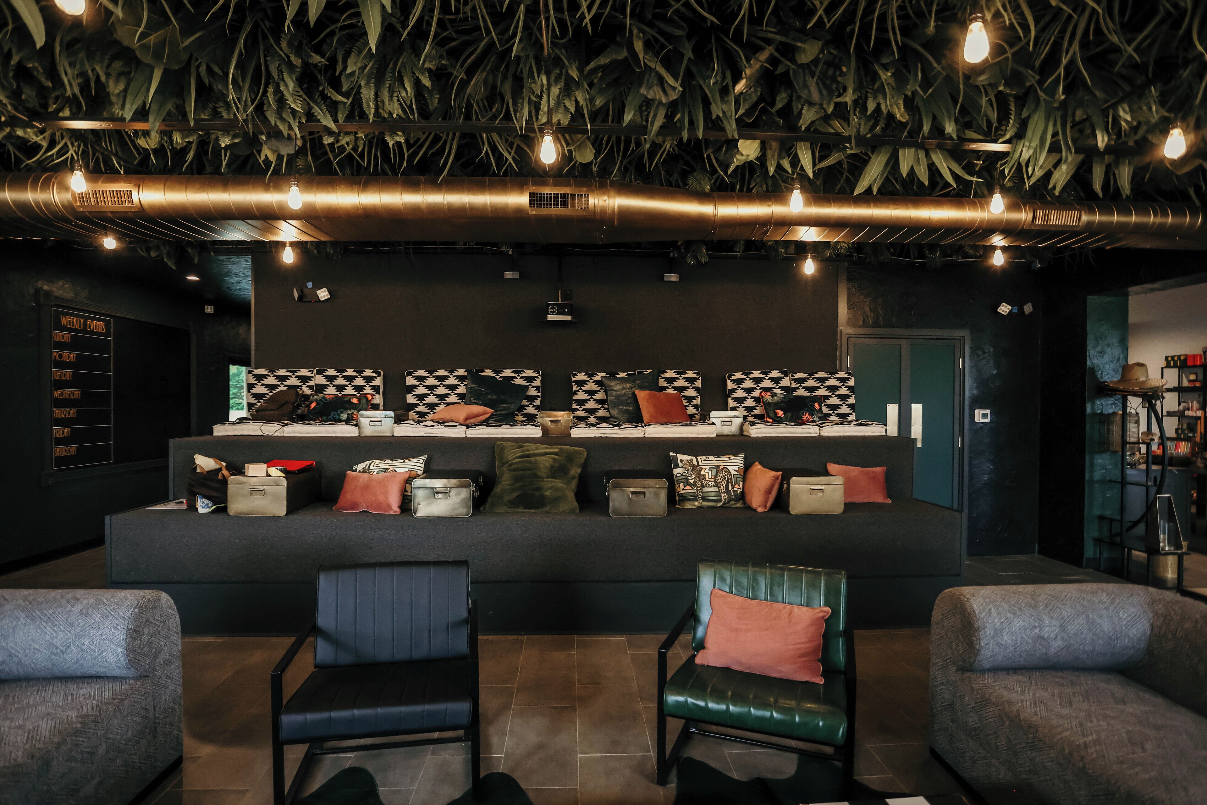 A modern lounge area with a sofa set, chairs, and a wall with patterned cushions.