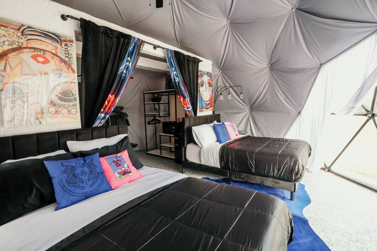 A tented room with two beds, black and white bedding, and a blue rug.