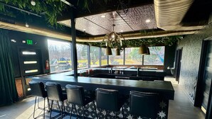 A modern bar area with a large island, bar stools, and a view of the outside. - DayDreamer Domes (South Haven)