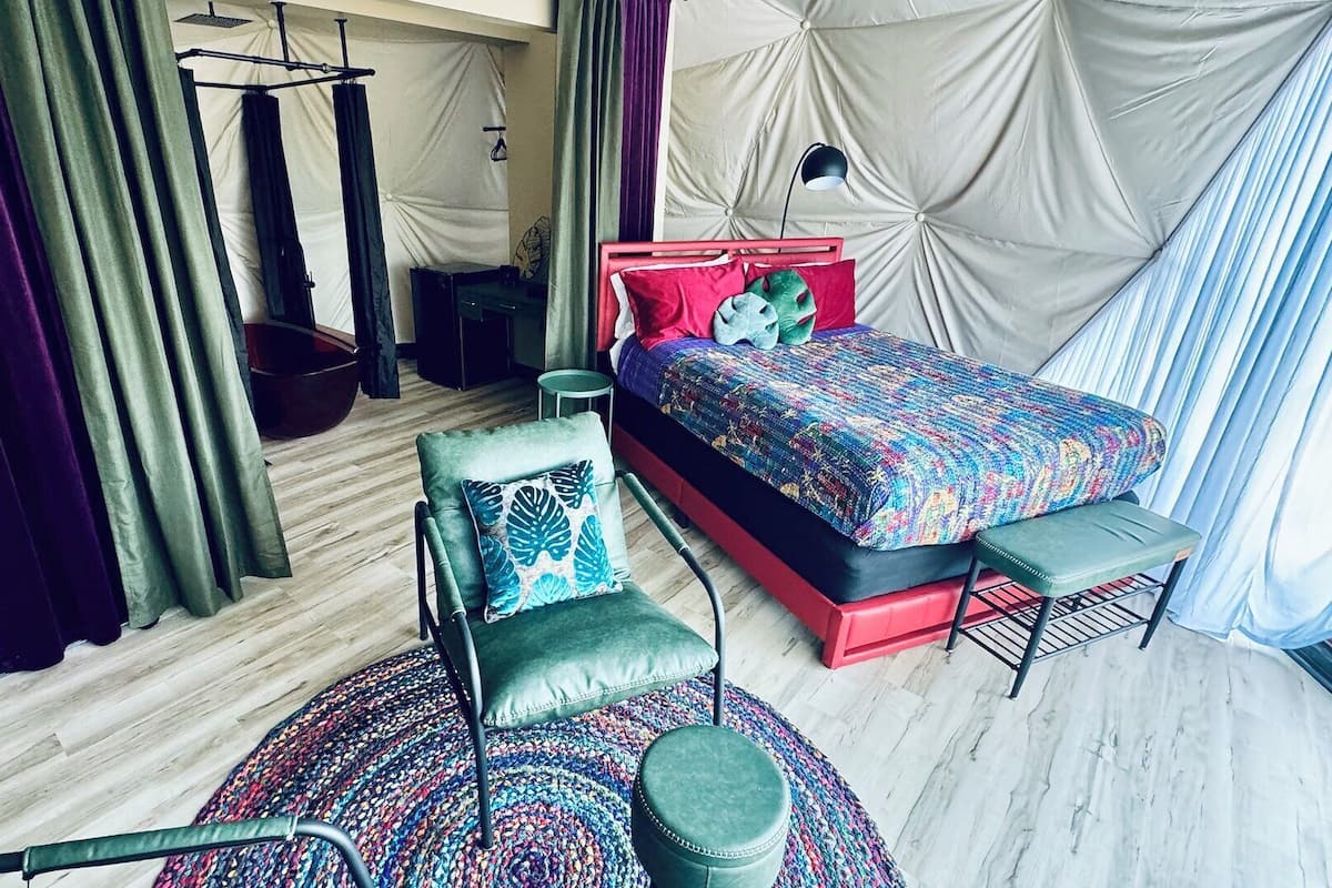 A modern bedroom with a bed, a chair, a hanging chair, and a small table.