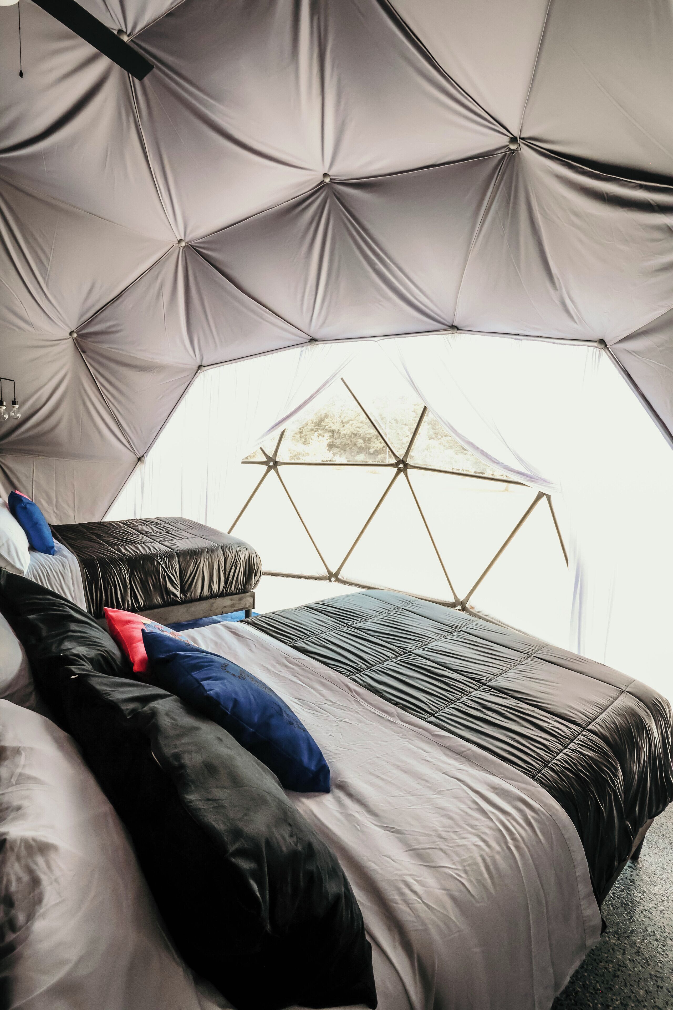 Un hébergement sous tente comprenant un lit, des oreillers et une fenêtre en forme d’étoile.