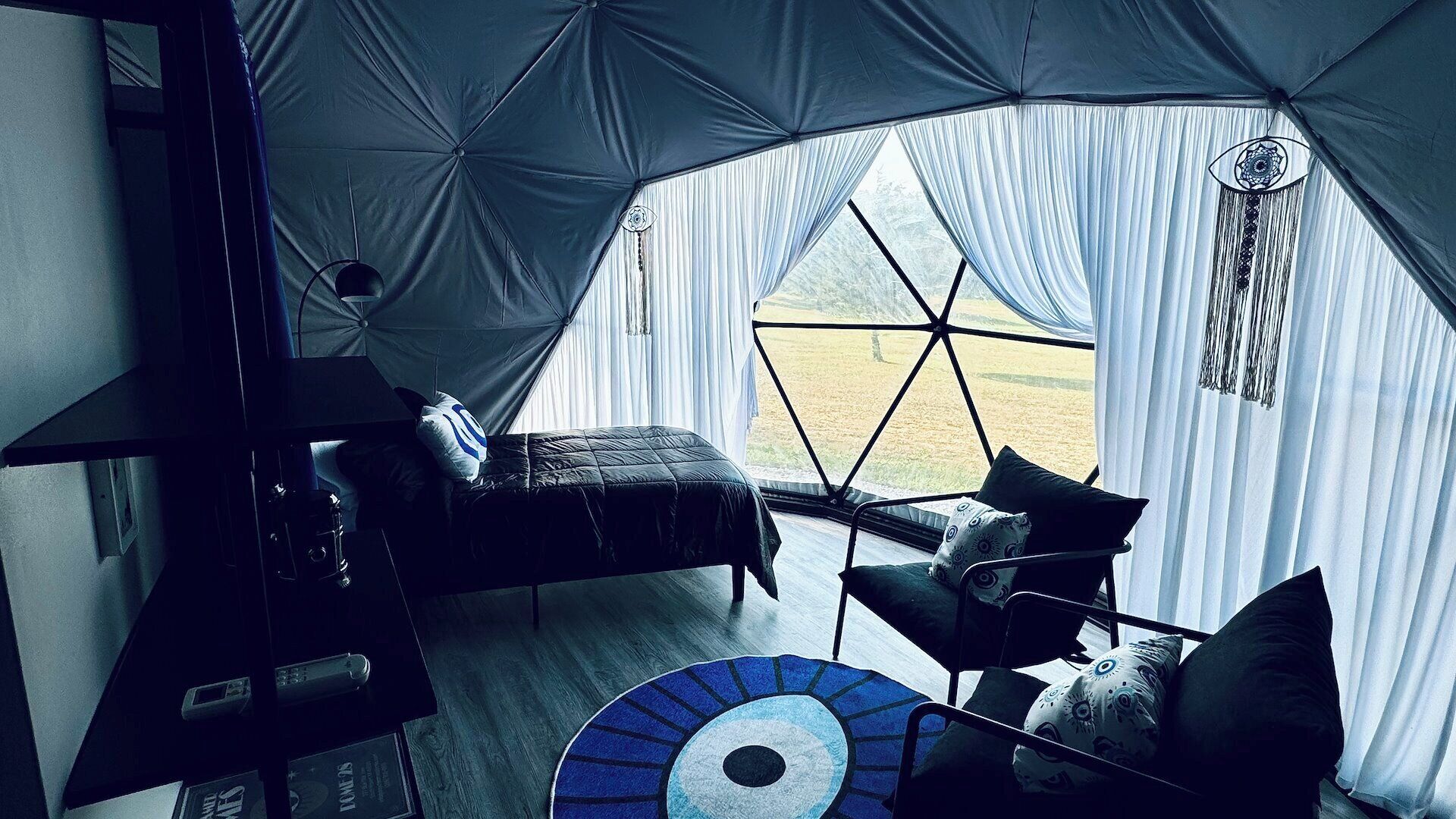 A tented room with a bed, a small table, and a chair.