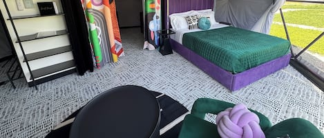 Um quarto tipo tenda com uma cama, uma escrivaninha e uma cadeira.