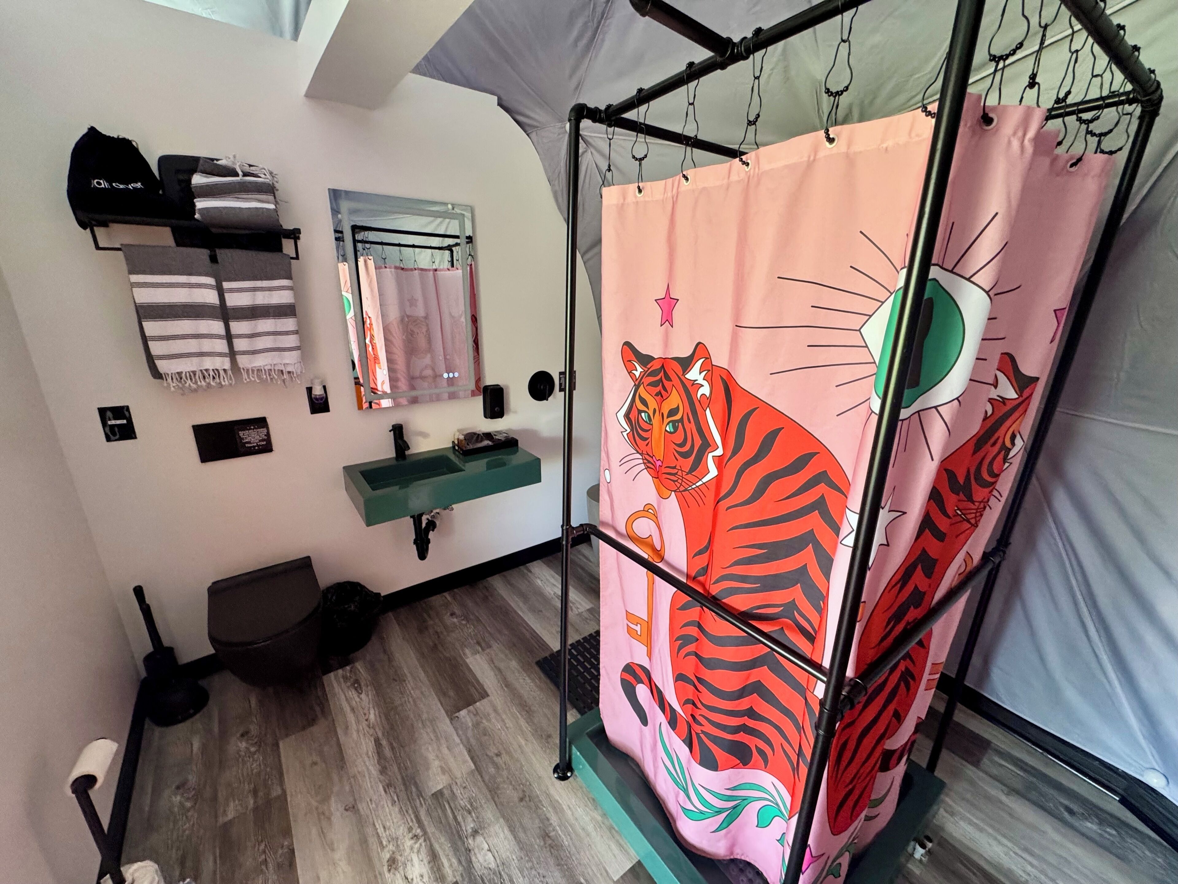 A bathroom with a sink, mirror, towel rack, and a shower curtain with a tiger design.