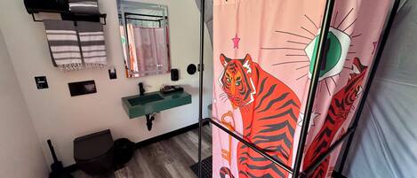 A bathroom with a sink, mirror, towel rack, and a shower curtain with a tiger design.
