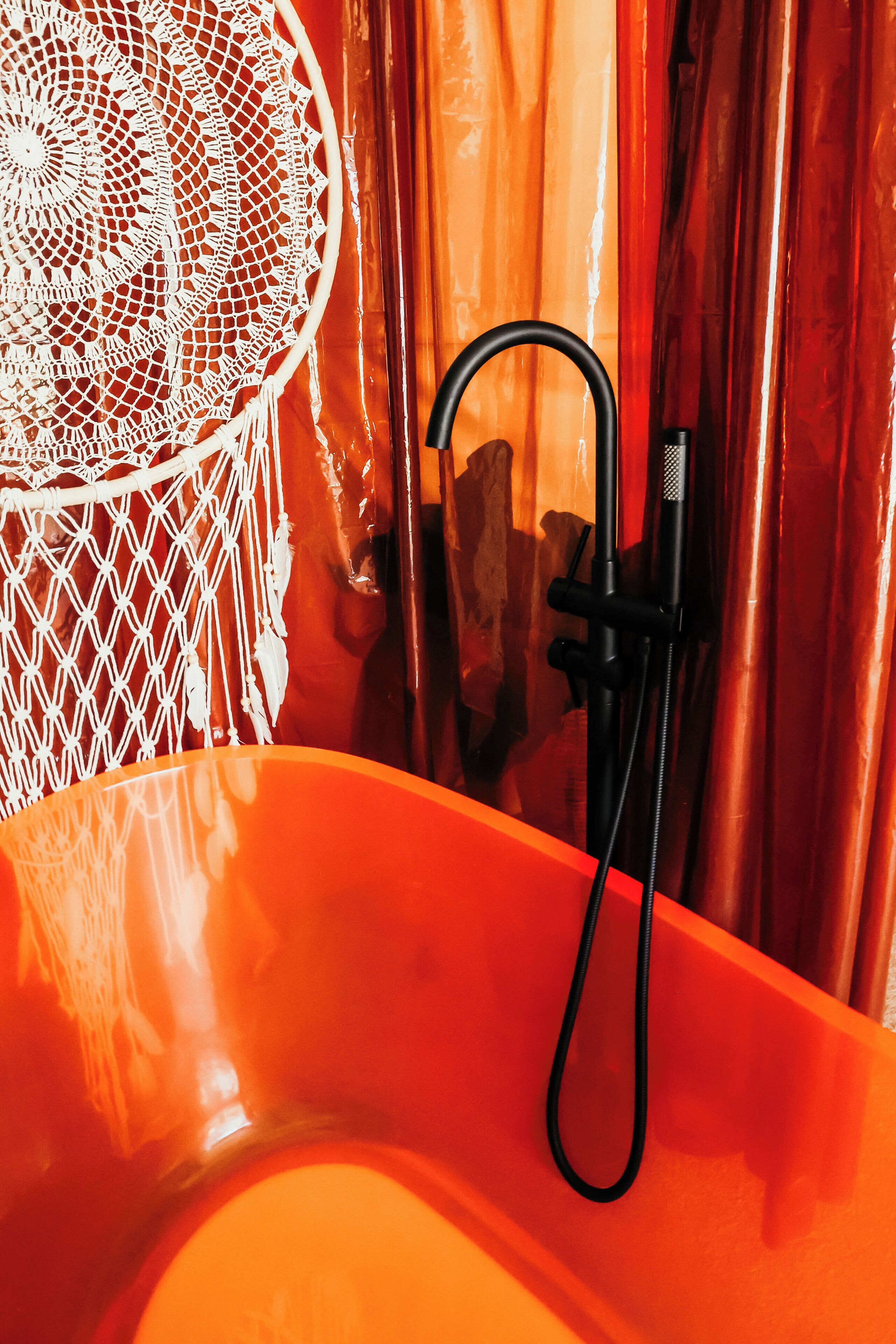 Un bagno con una vasca, una doccia e un tendaggio in pizzo bianco.