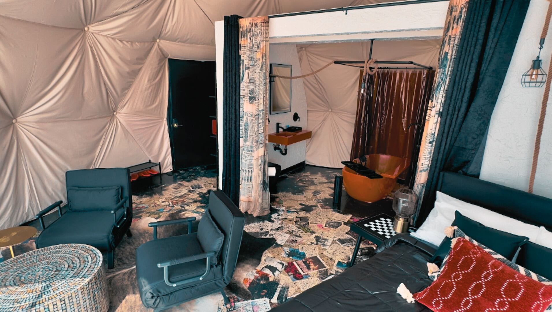 Una habitación pequeña con cama, una mesita, una silla y una maleta.