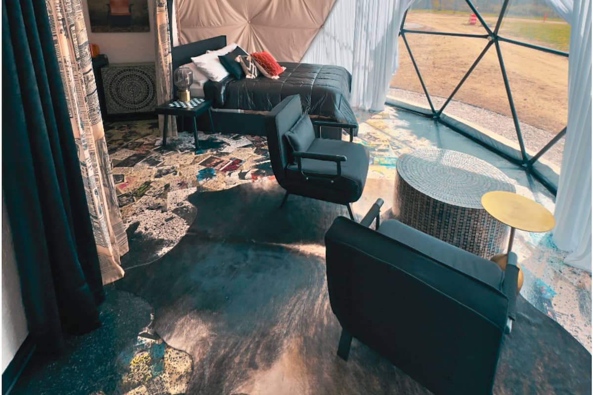 A tented room with a bed, chairs, a table, and a ceiling fan.