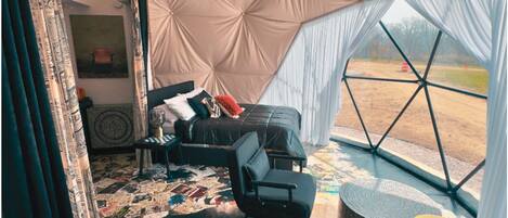 A tented room with a bed, chairs, a table, and a ceiling fan.