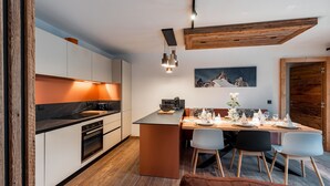 A modern kitchen with white cabinets, a black countertop, and a wooden ceiling beam. - Thom's apartment - LES GETS: right in the center and at the foot of the slopes (Les Gets)