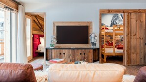 A cozy living room with a large TV, wooden furniture, and a red chair. - Thom's apartment - LES GETS: right in the center and at the foot of the slopes (Les Gets)